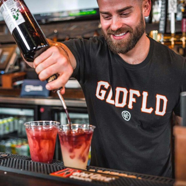 Bartender pour mixed cocktail drink at the bar with smile